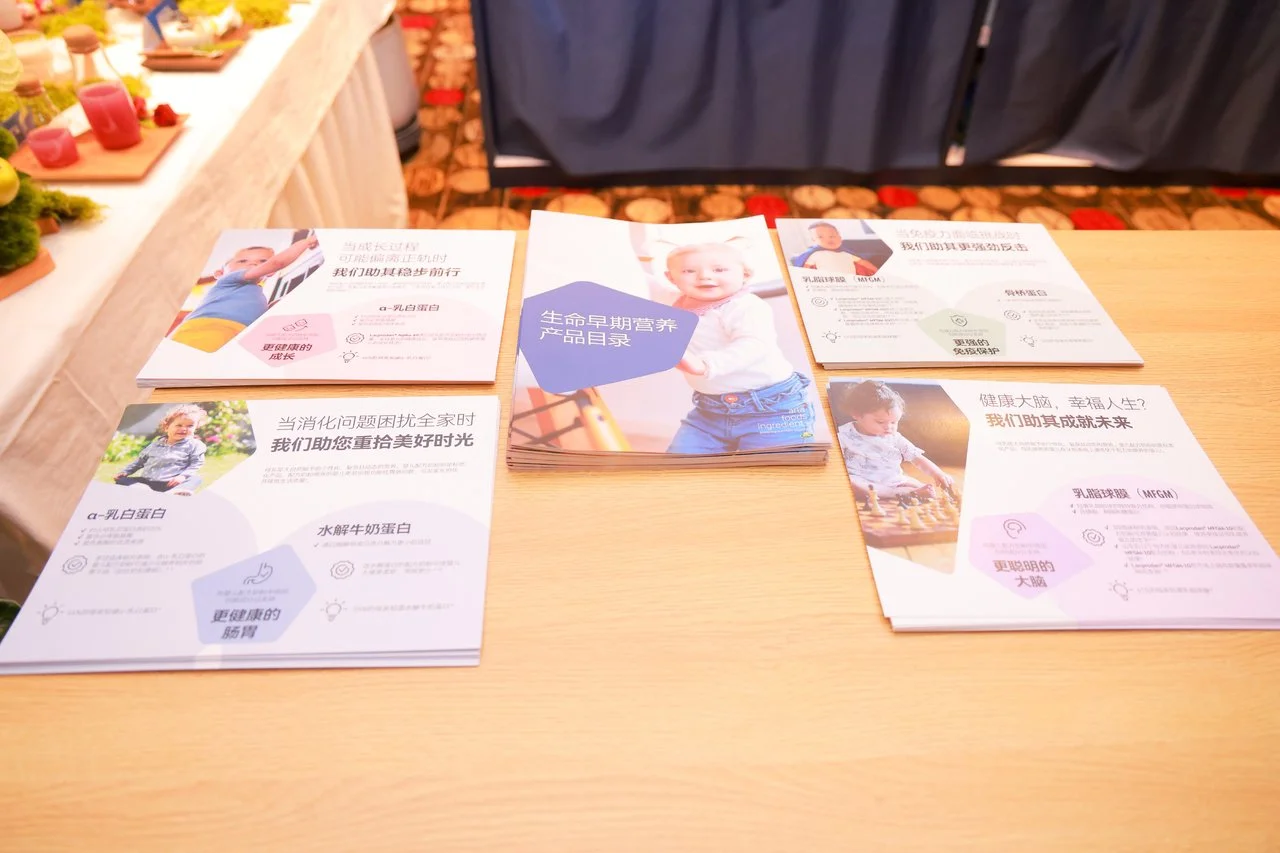 Brochures and flyers related to early childhood nutrition and development are displayed on a wooden table.
