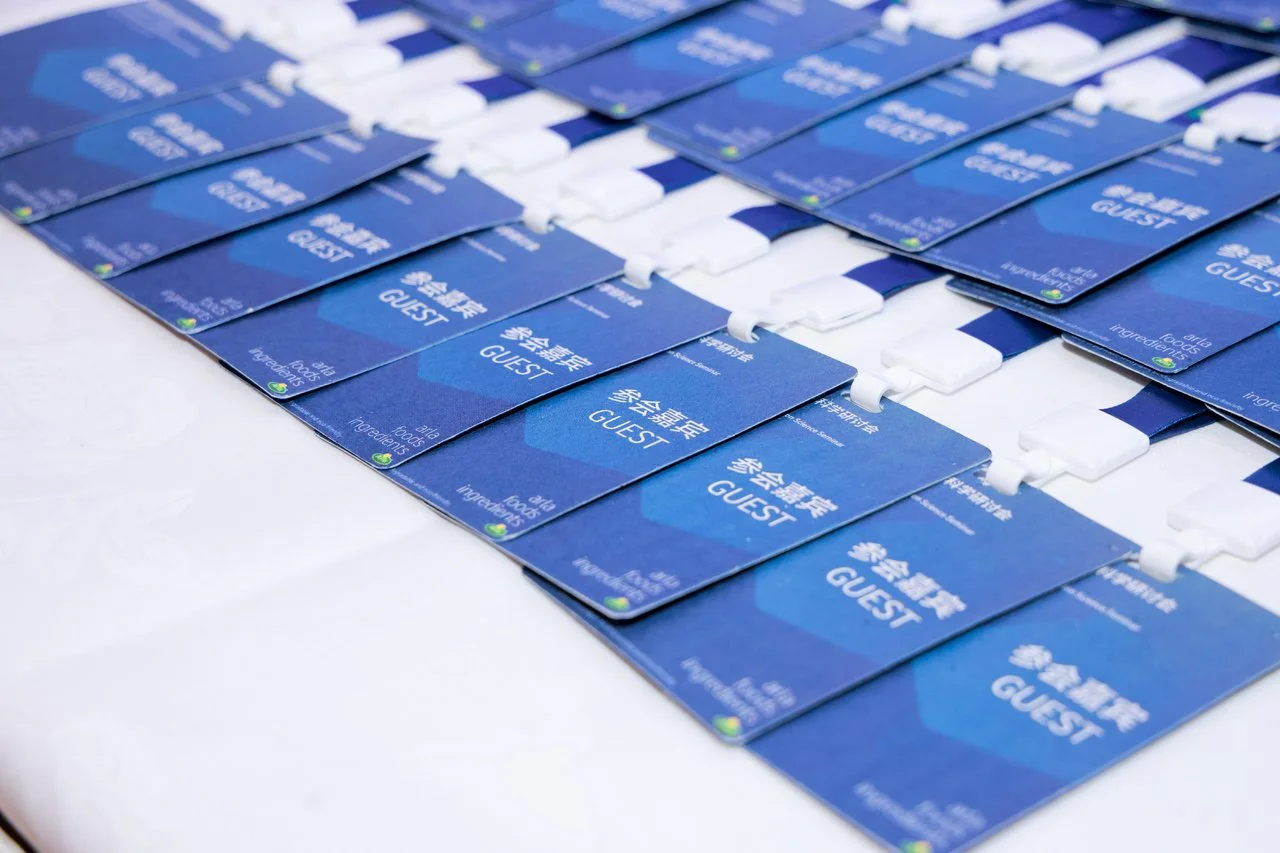Multiple blue event badges with the word 'GUEST' in English and Chinese, arranged in neat rows on a white table.
