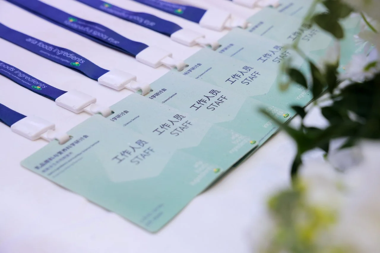 Event staff badges and lanyards lying on a table with some greenery in the foreground.