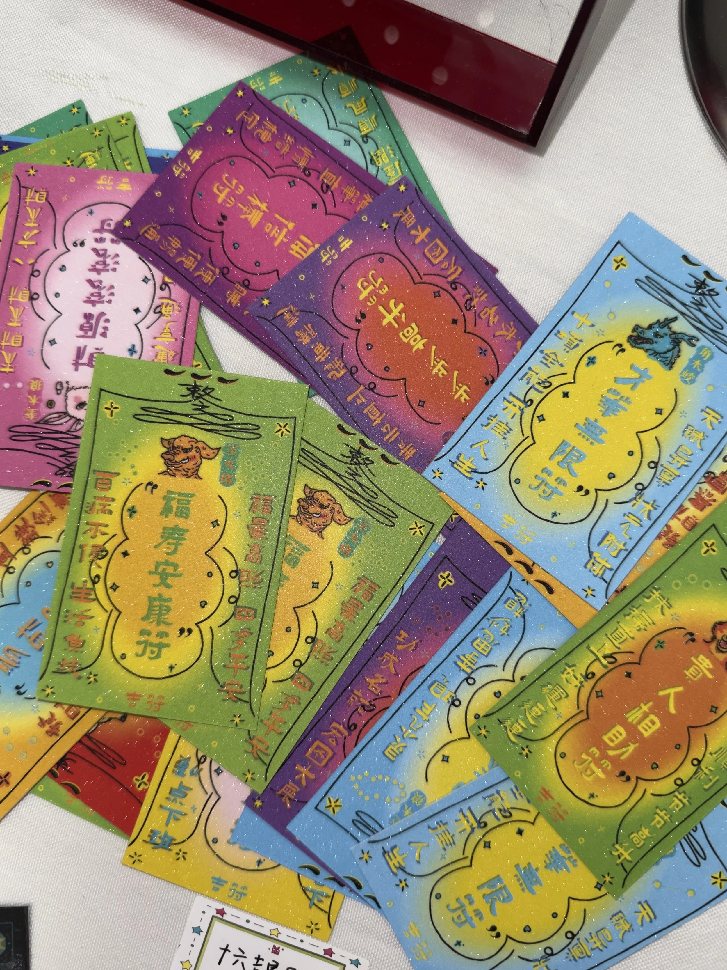 Colorful paper fortune slips with Chinese characters and illustrations of a tiger and a dragon, spread out on a white surface.