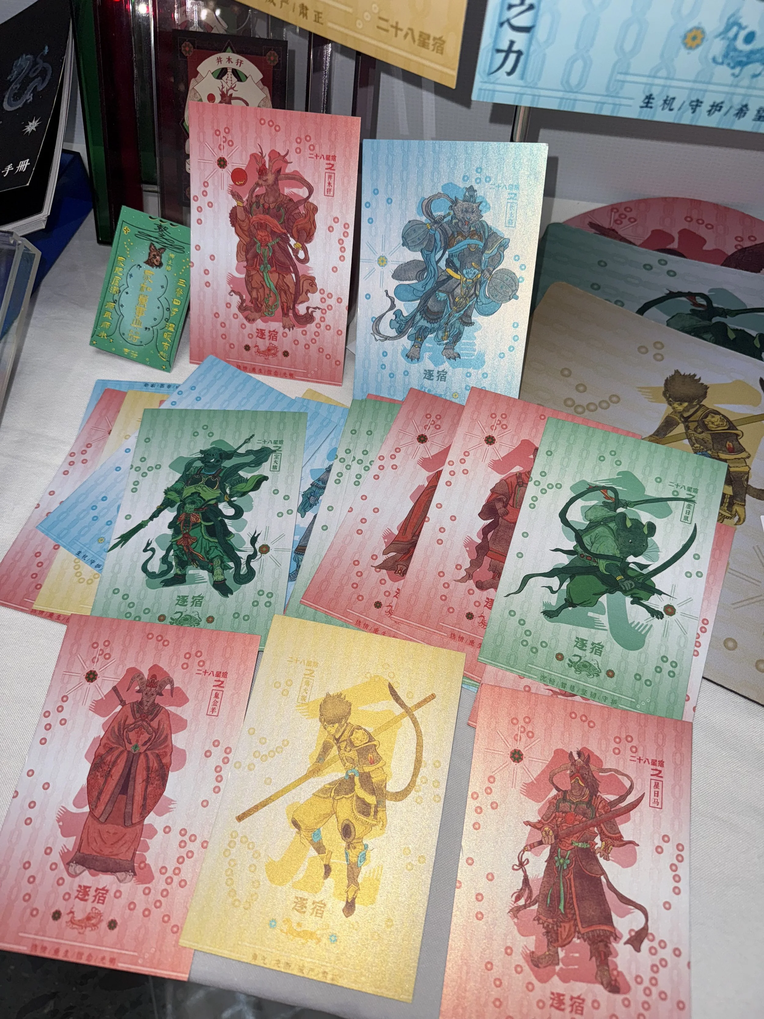 Colorful illustrated paper bills or cards with traditional Japanese or Chinese characters and warrior images, arranged on a surface.